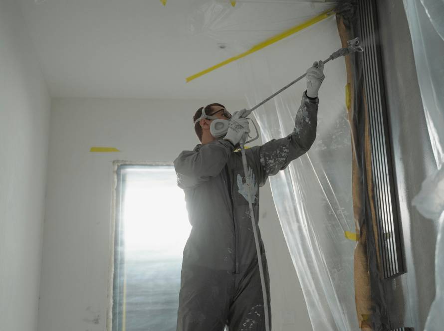 Ein Maler pinselt gekonnt auf einer Leiter die Wand an