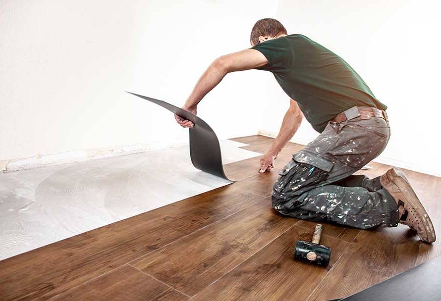 Ein Handwerker verklebt gekonnt Vinylboden