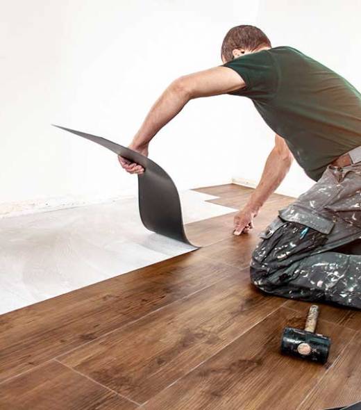 Ein Handwerker verklebt gekonnt Vinylboden